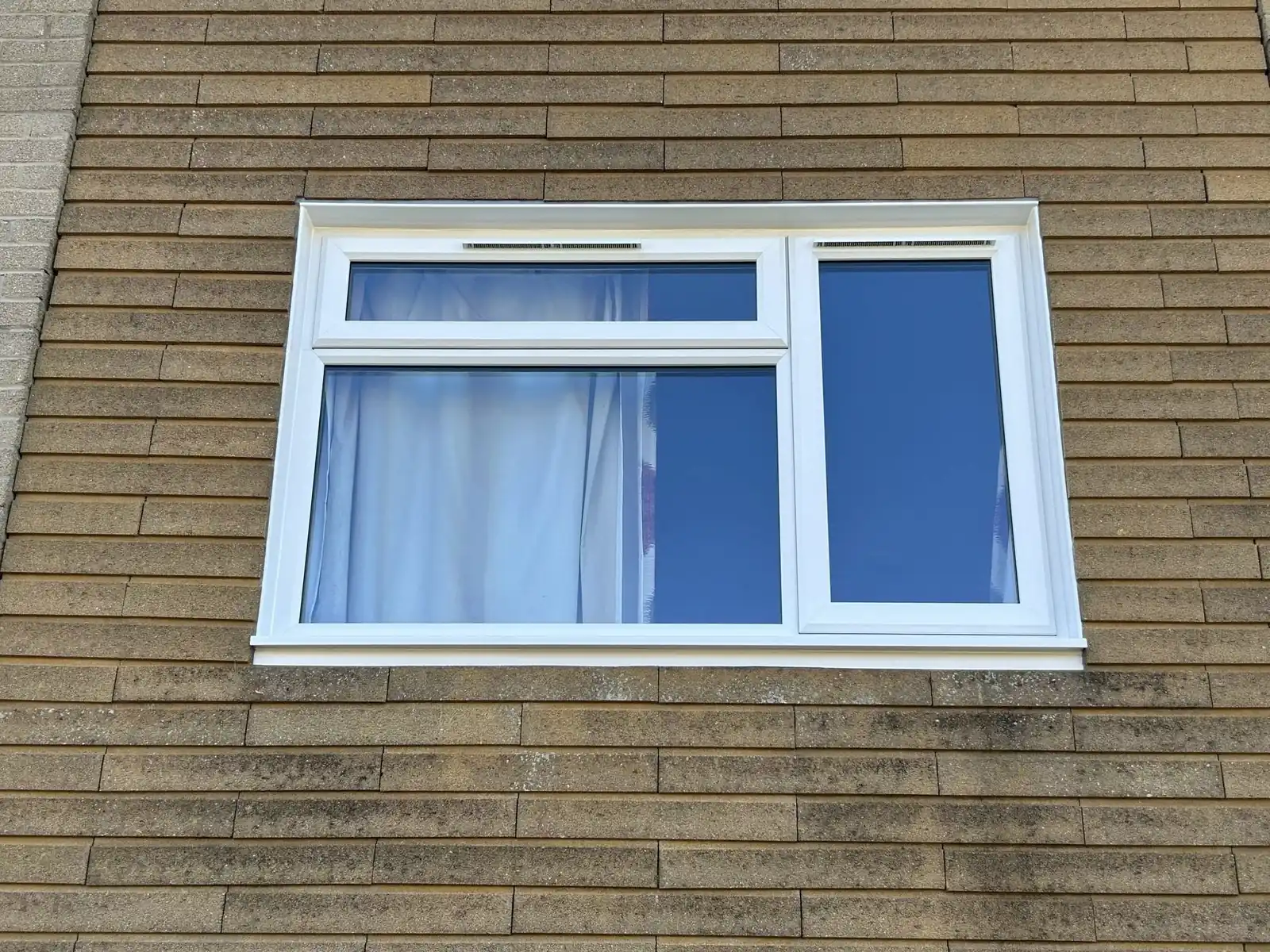 White asymmetric casement window in a brick wall